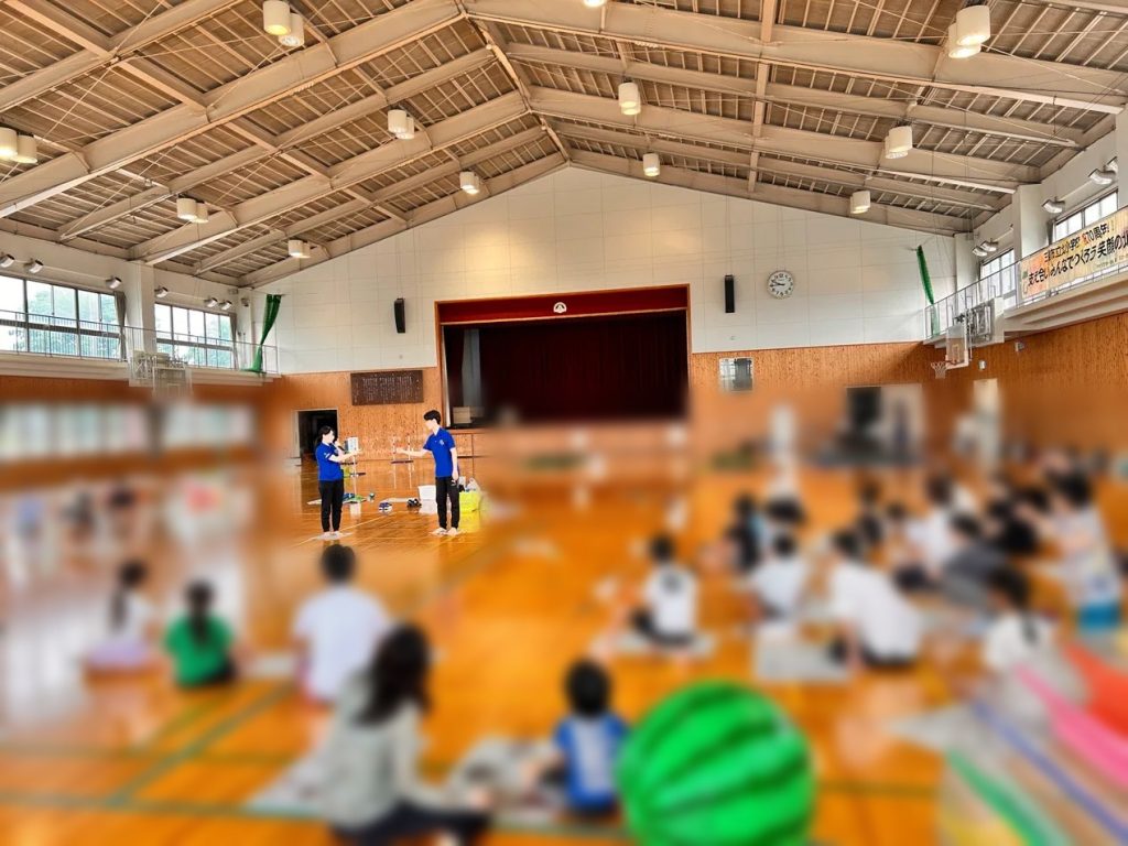 小学校の体育館での子どもの運動教室で指導するスタッフ